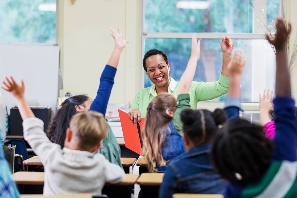 Teacher educating students in classroom with hands raised