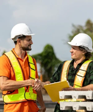 two men in hard hats and high-vis vests performing a handshake