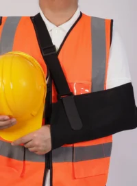 person in high visibility vest with arm in a sling holding a hard hat