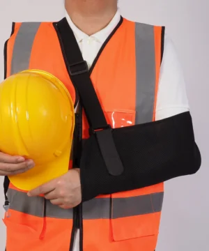 person in high visibility vest with arm in a sling holding a hard hat