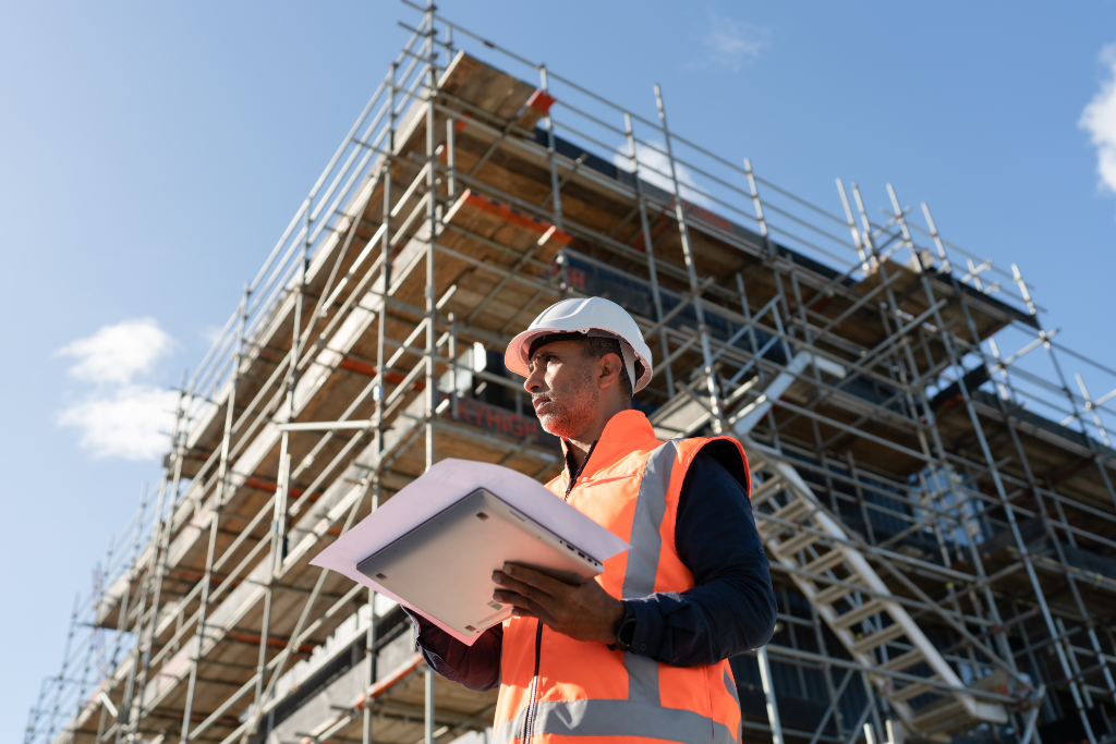 Construction Worker with laptop and building in the background