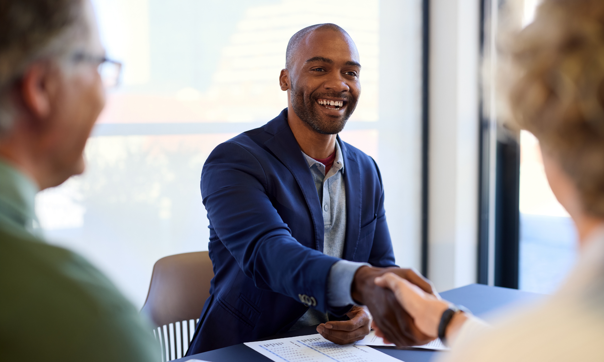businessmen handshake at desk with documents